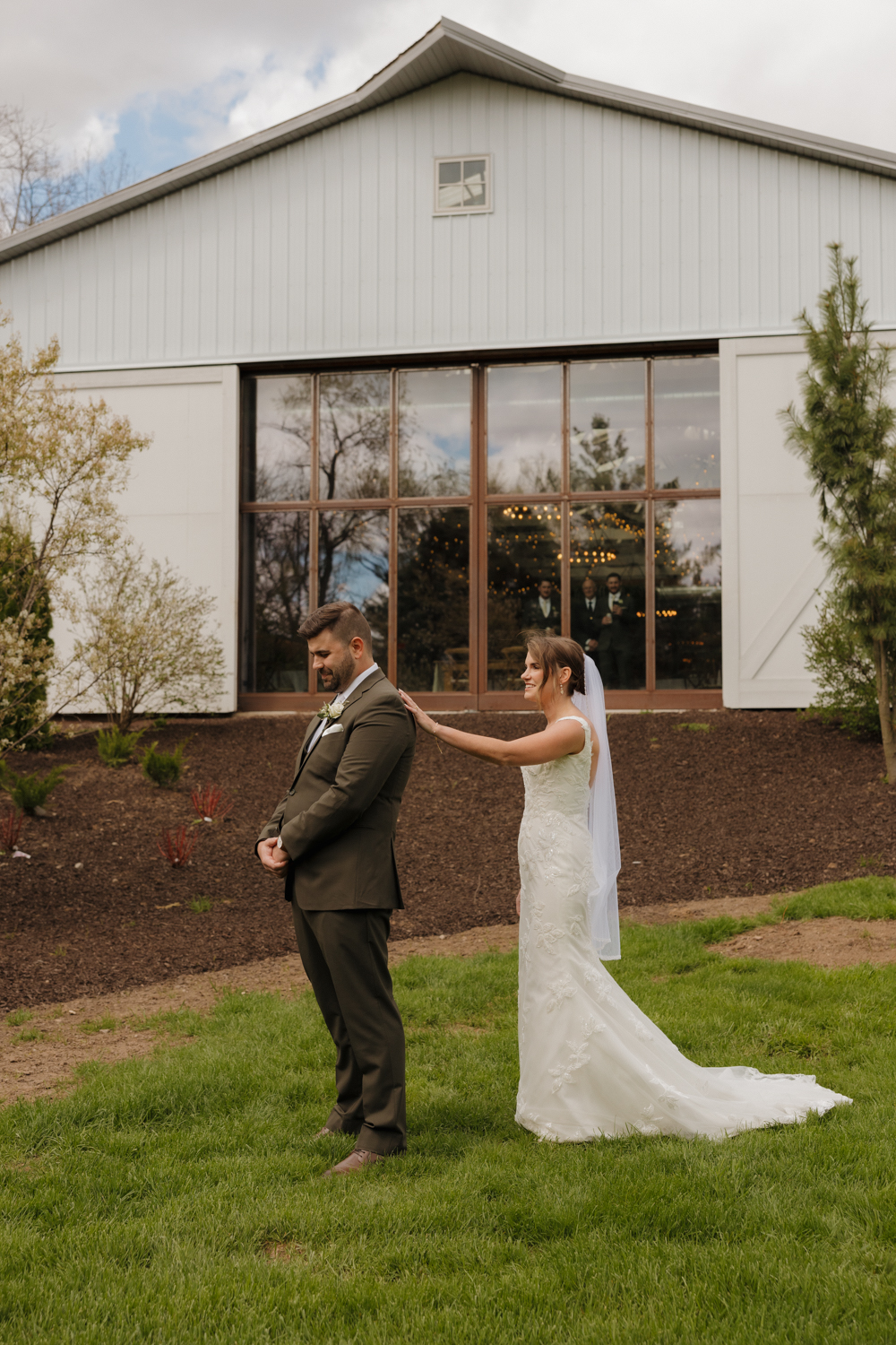Bride tapping the groom on the shoulder for their first look outside Boxed and Burlap Delavan.