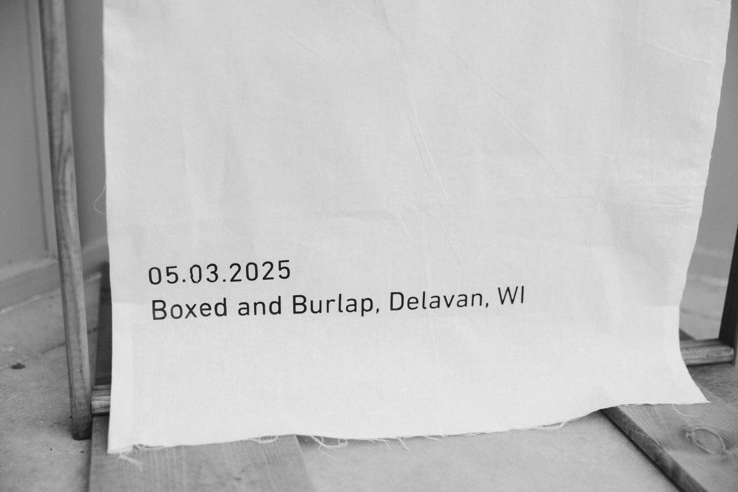 Minimal wedding linen detail with “Boxed and Burlap, Delavan, WI” printed in modern typography.