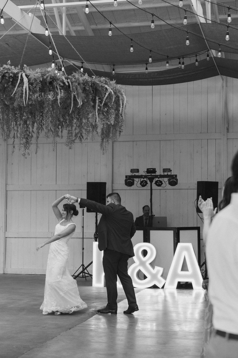 Bride twirling on the dance floor in front of illuminated marquee letters during the reception.