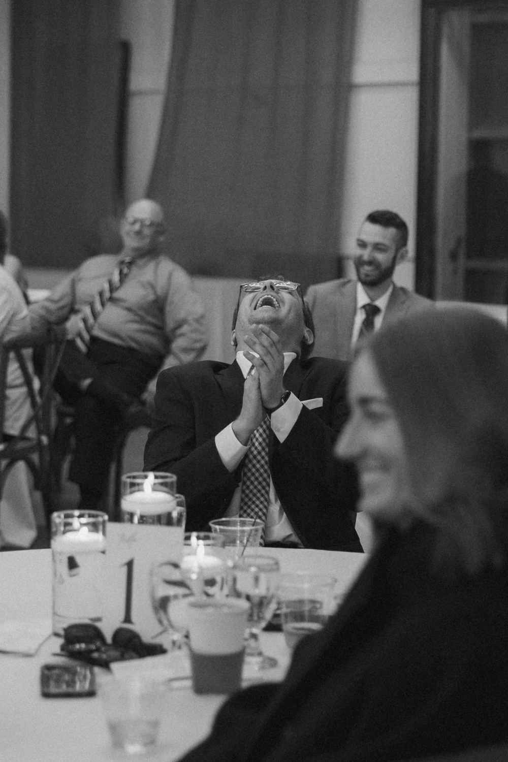 Guest laughing with head tilted back during a heartfelt and funny wedding toast.