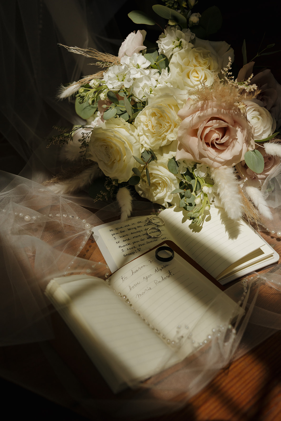 Wedding bouquet with ivory and blush roses styled with handwritten vows and rings, photographed by a madison wisconsin wedding photographer.