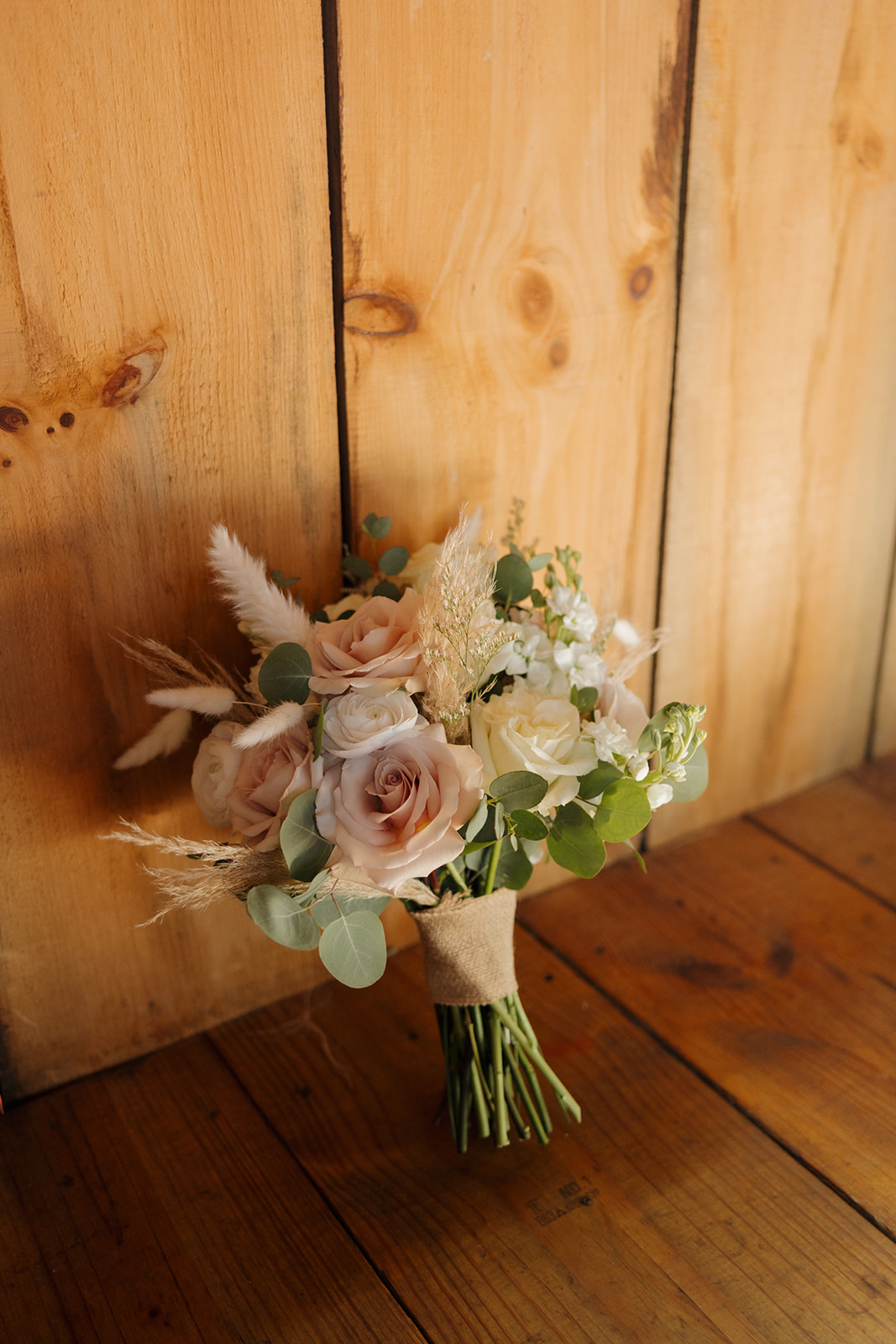 Blush and ivory rose bridal bouquet resting against a rustic wooden wall, captured by a madison wisconsin wedding photographer.
