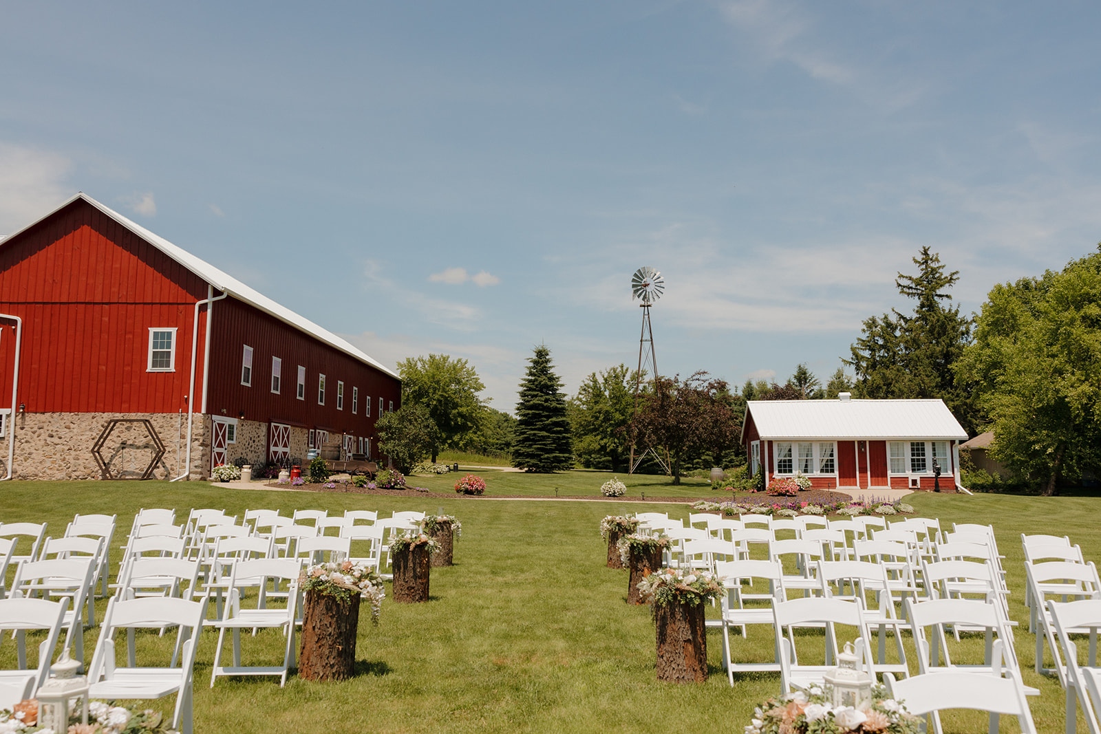 Outdoor wedding ceremony chairs set up in front of a red barn and windmill on a sunny day, photographed by a madison wisconsin wedding photographer.
