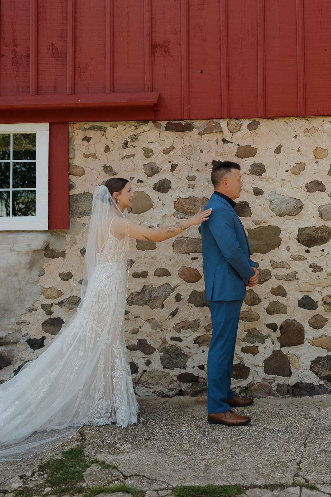 Bride tapping father on the shoulder for their first look outside a rustic barn, photographed by a madison wisconsin wedding photographer.