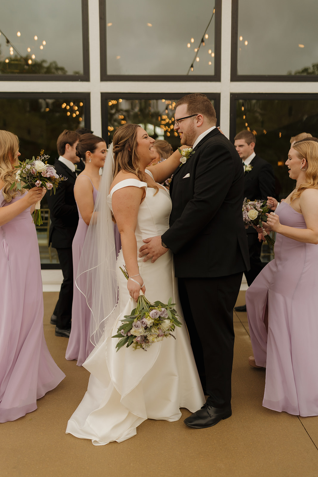 Bride and groom smiling at each other surrounded by bridesmaids and groomsmen at wedding venues in Wisconsin