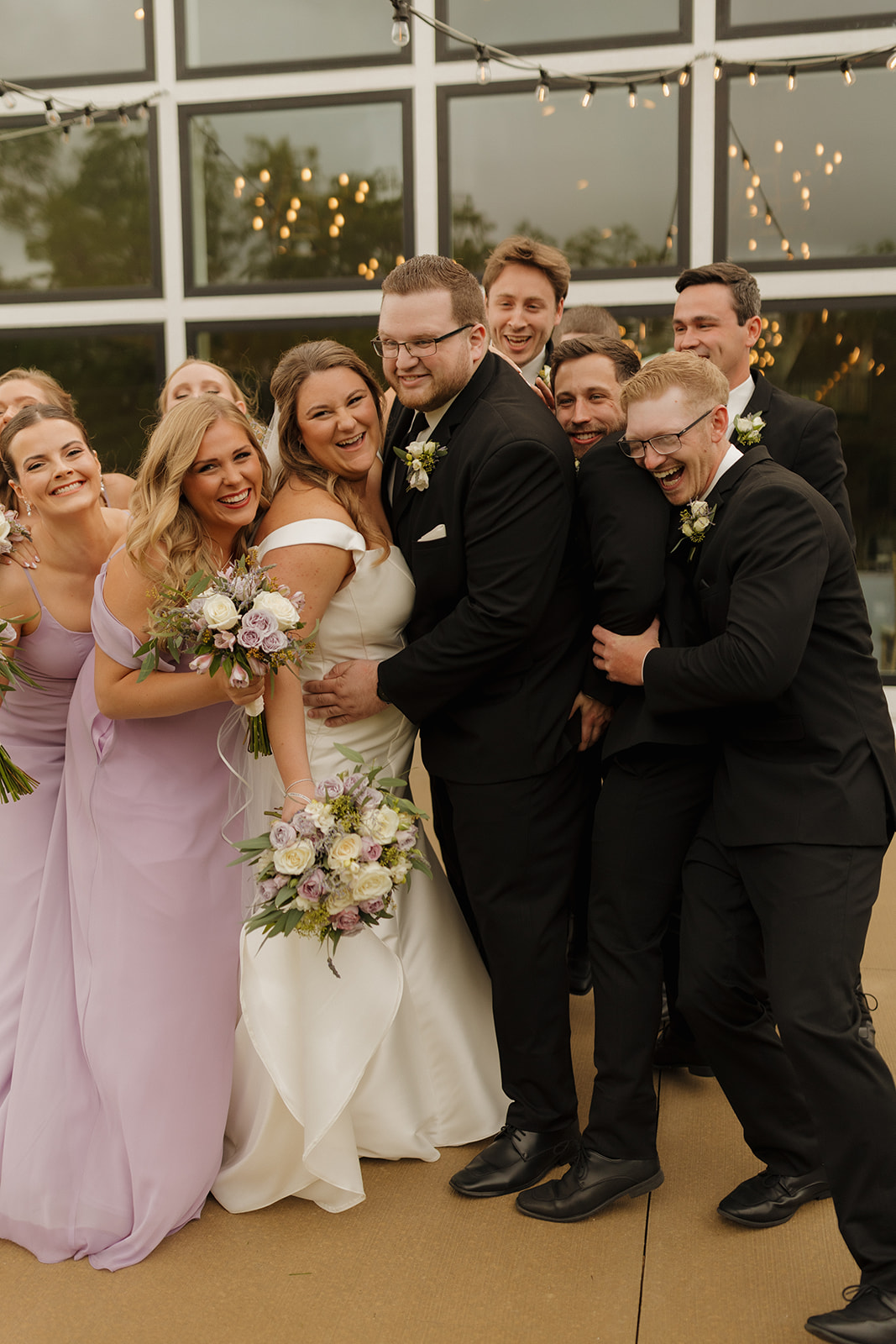 Bride and groom laughing with wedding party outside modern wedding venues in Wisconsin