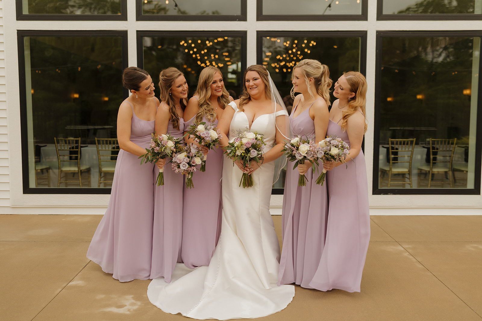 Bride and groom smiling at each other surrounded by bridesmaids and groomsmen at wedding venues in Wisconsin