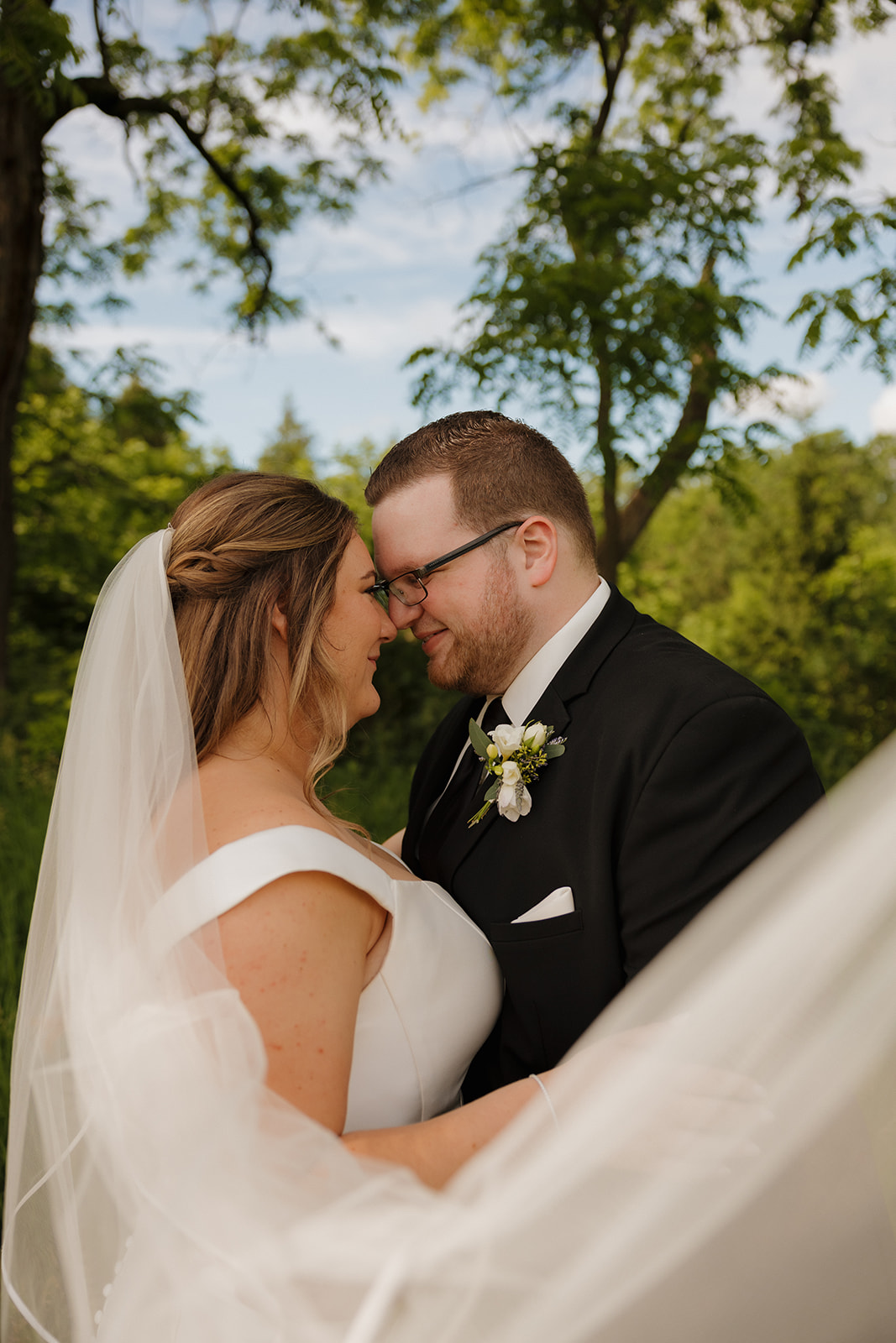 Bride and groom embracing in a green field during sunset portraits