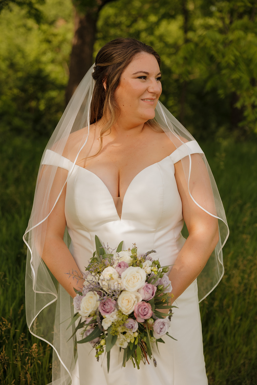 Bride walking through open field in wedding dress during golden hour