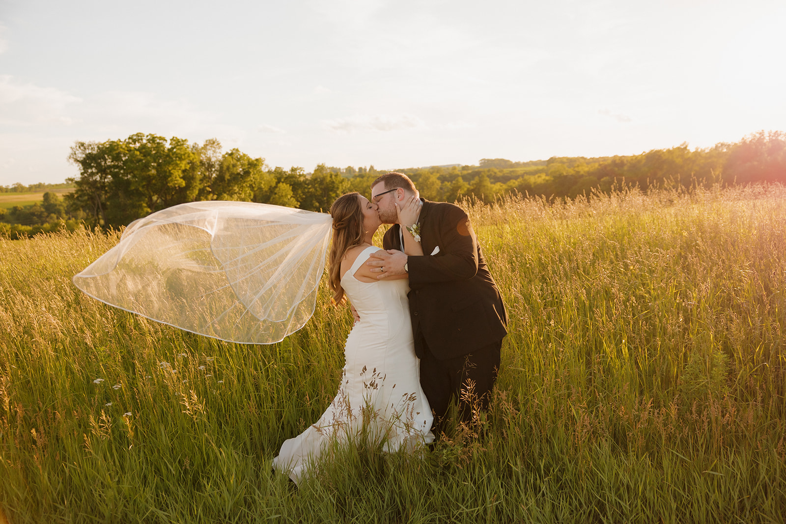 Newlyweds kissing in a golden field at sunset at wedding venues in Wisconsin