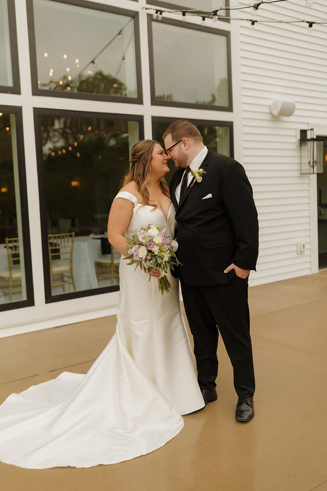 Bride and groom kissing beneath string lights at wedding venues in Wisconsin