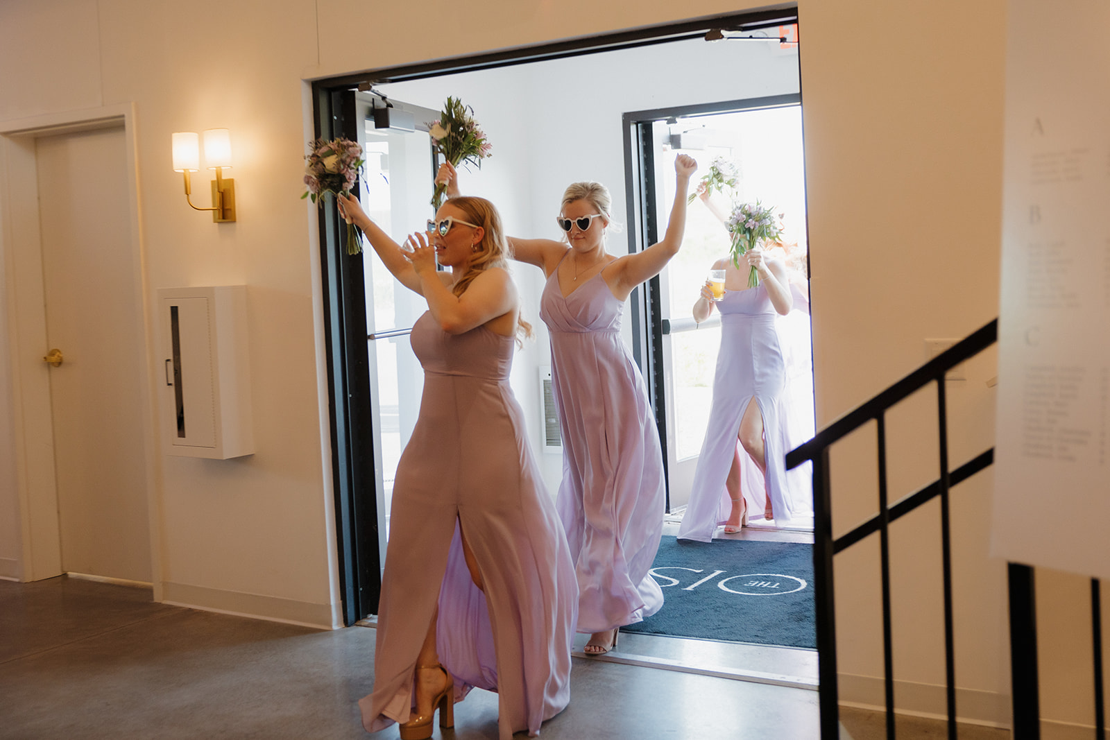 Bridesmaids entering reception with bouquets and sunglasses