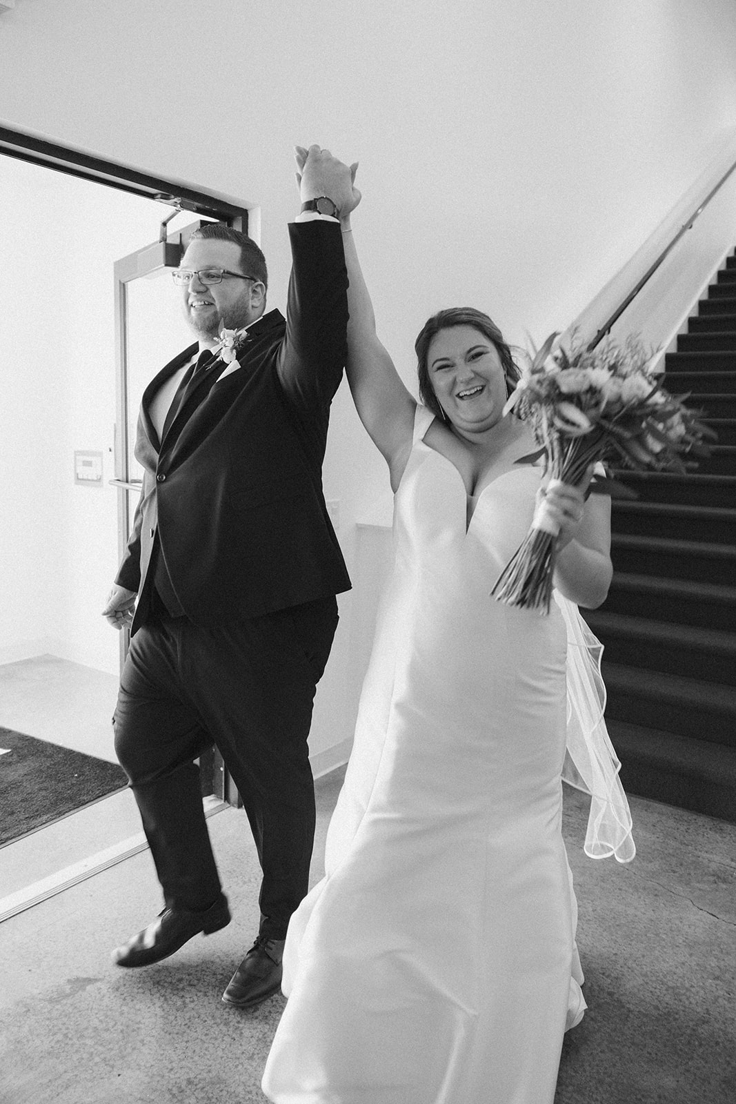 Bride and groom entering reception with hands raised inside wedding venues in Wisconsin