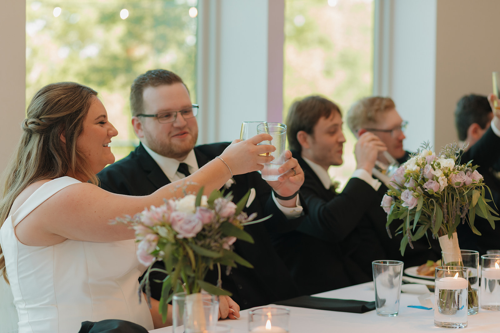 Bride and groom clinking glasses during reception speeches