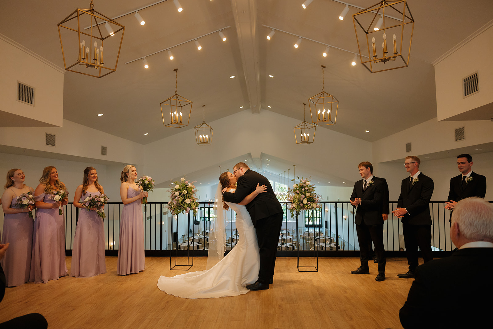 Bride and groom sharing first kiss under chandeliers at modern wedding venues in Wisconsin