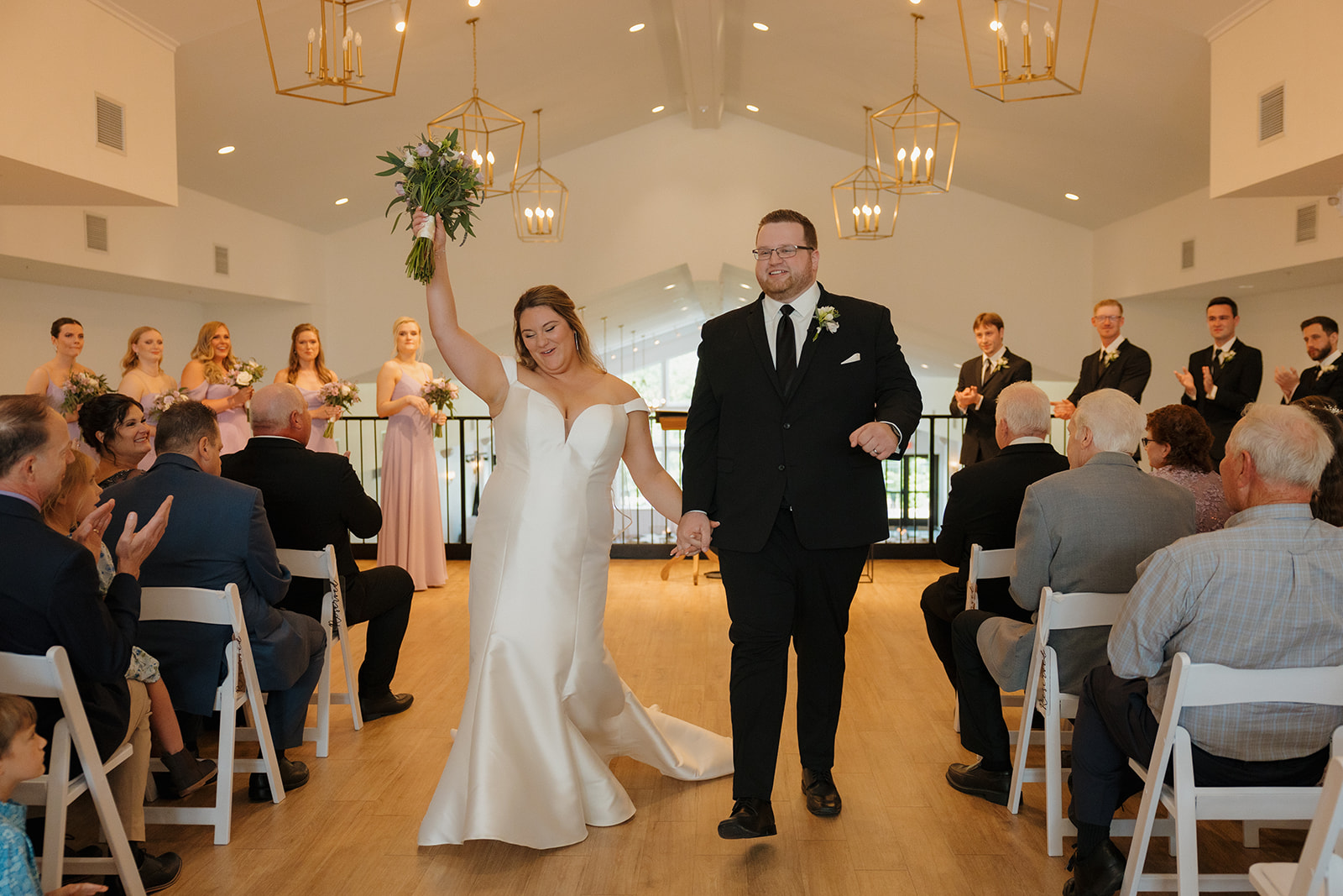 Newlyweds walking down the aisle as guests applaud at a Wisconsin wedding venue