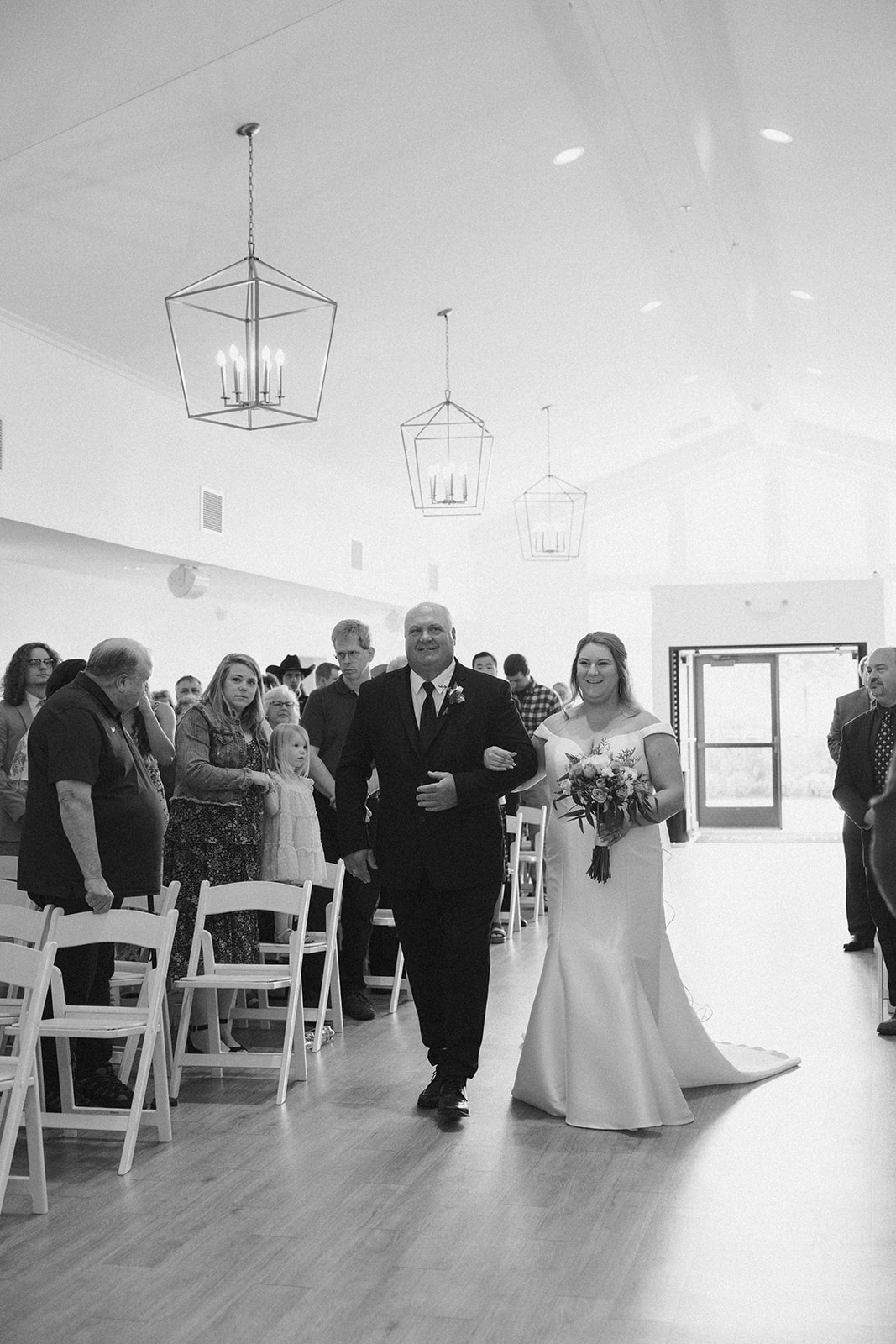 Bride and father walking down ceremony aisle in timeless black and white image