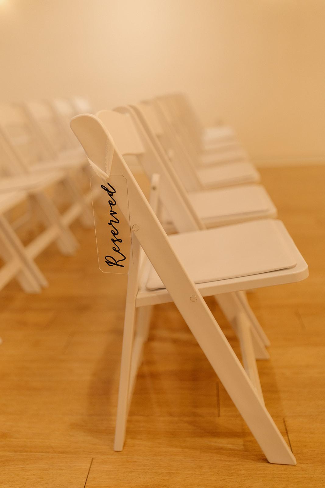 Reserved sign hanging on white ceremony chair in soft natural light