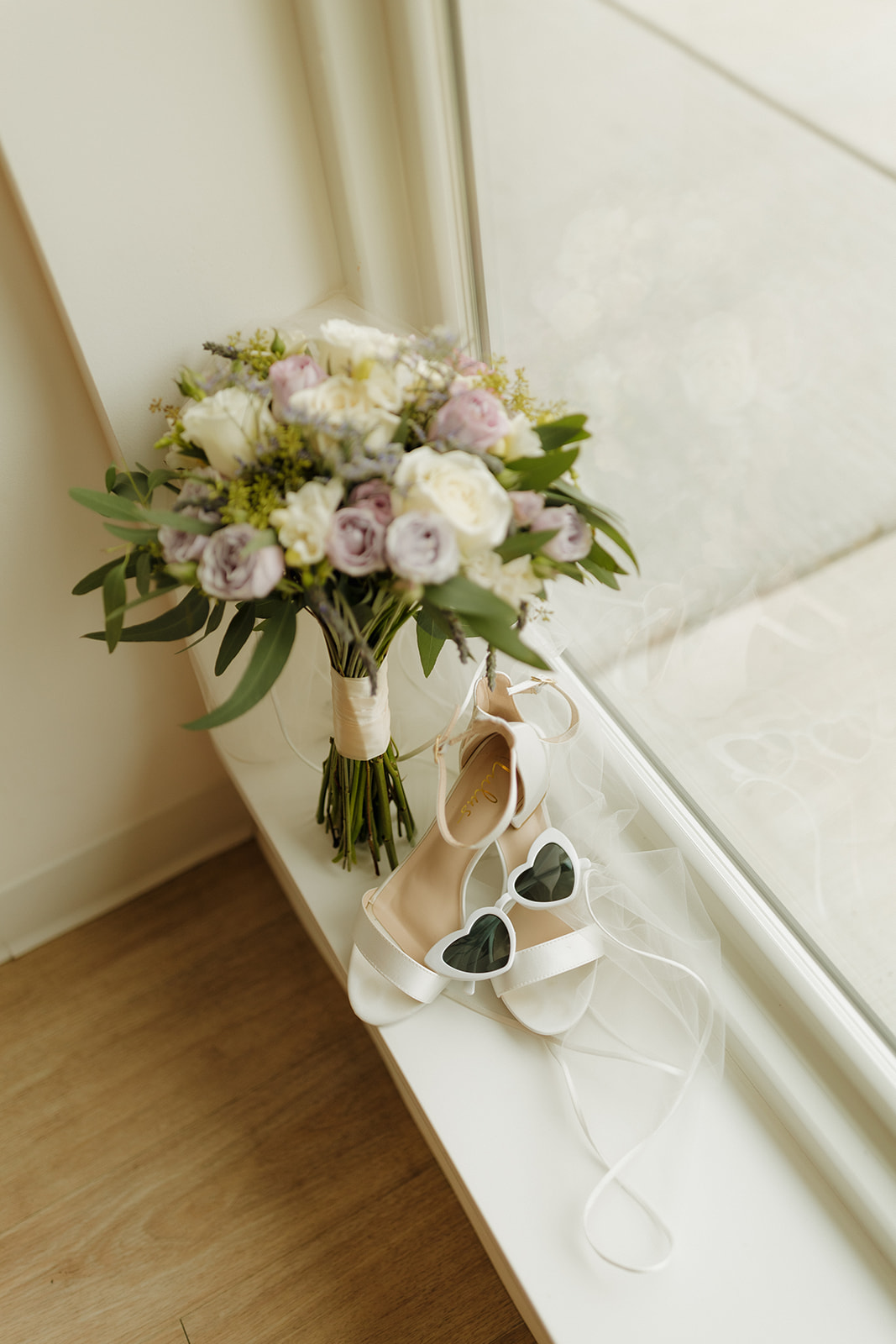 Bridal bouquet and wedding shoes styled in soft natural window light