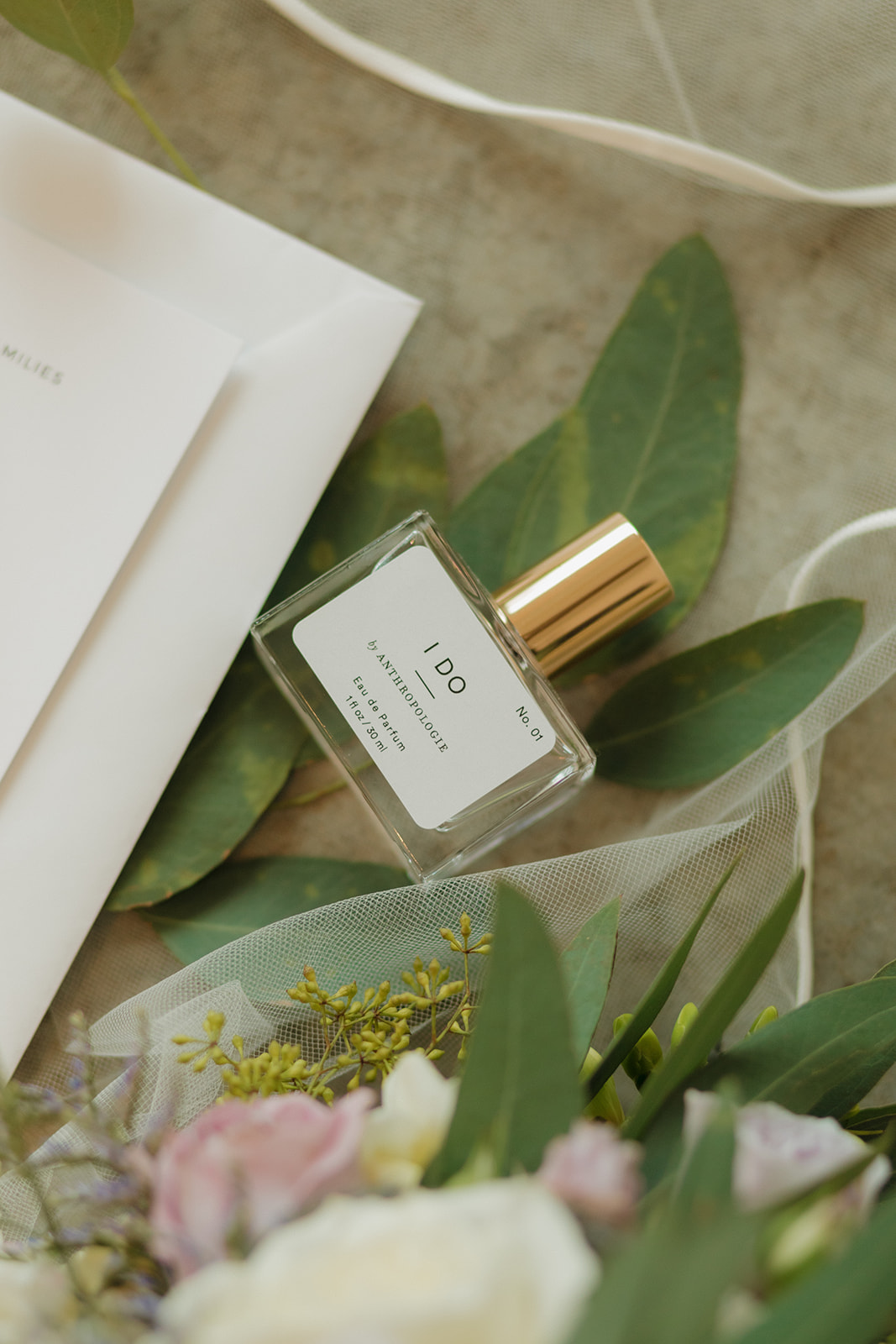 Bride’s perfume bottle styled with greenery and soft floral wedding details