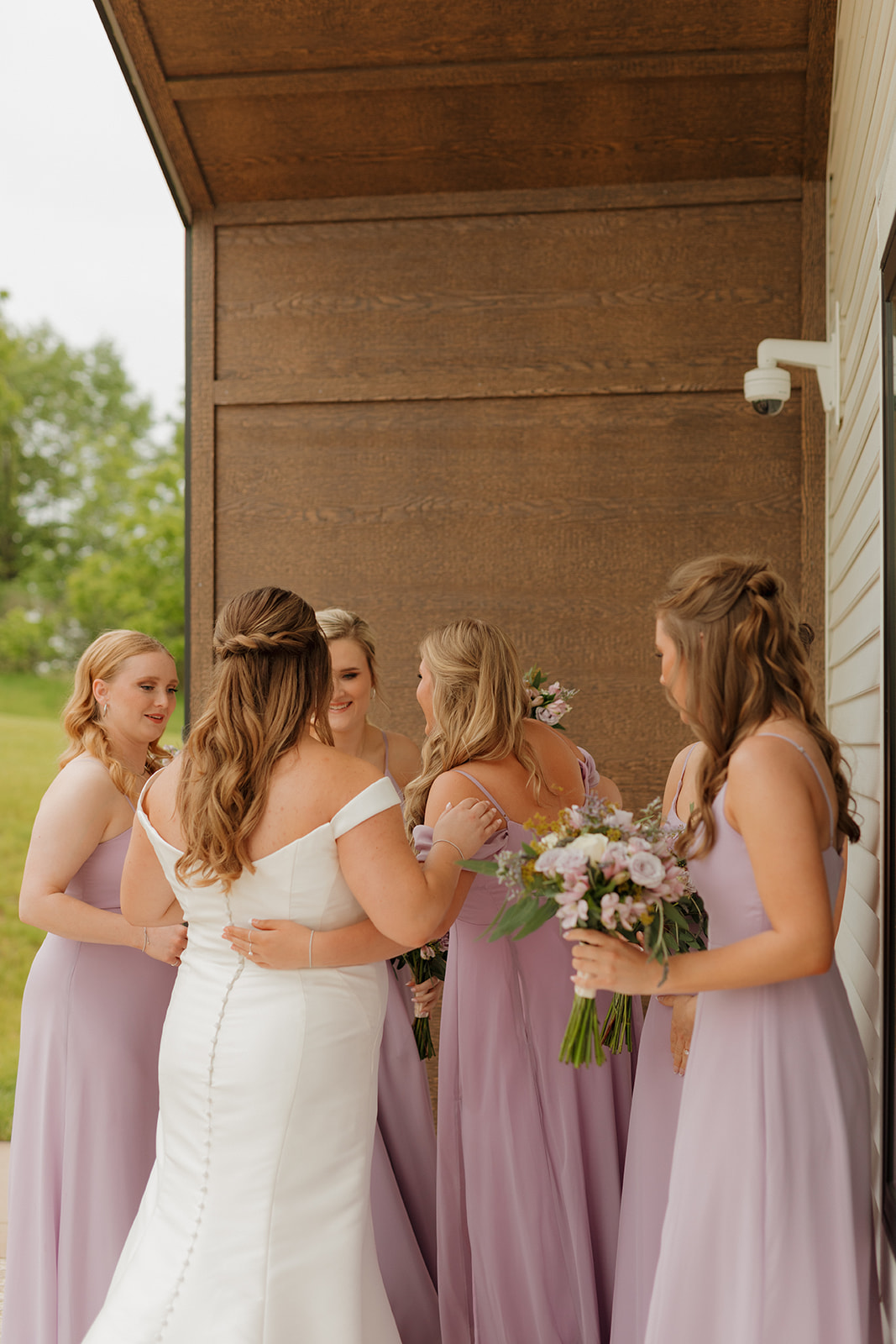 Bride hugging bridesmaids in soft lavender dresses at modern wedding venues in Wisconsin