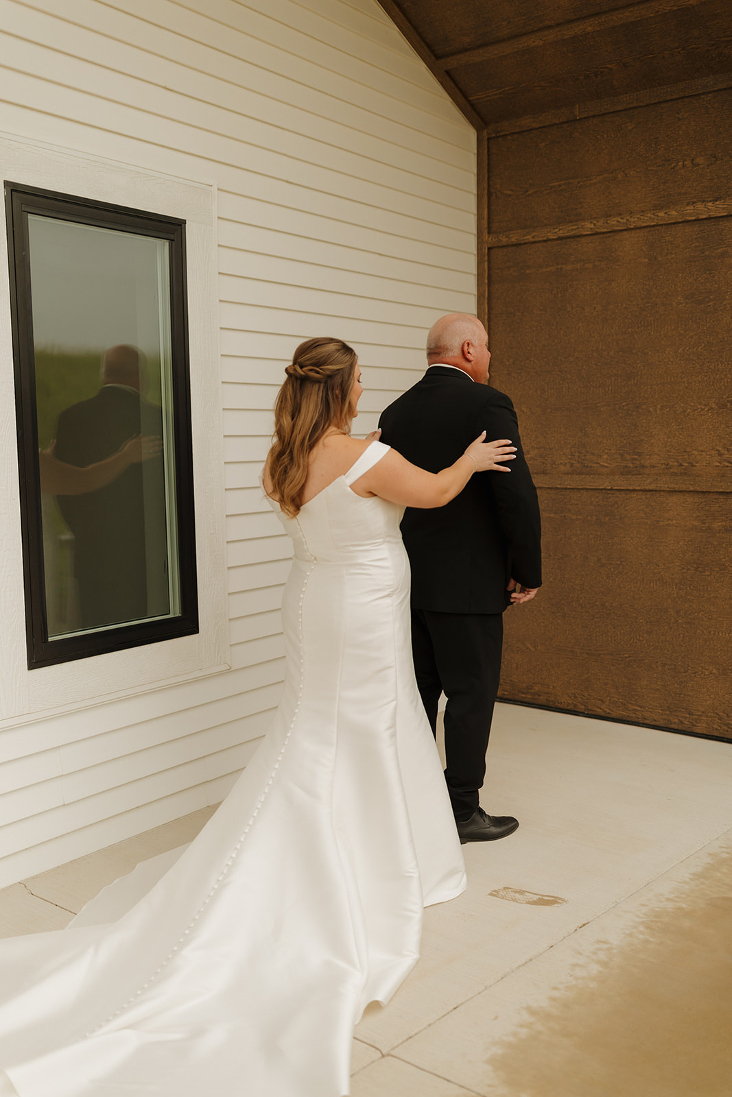Bride tapping her father’s shoulder for first look outside a Wisconsin wedding venue