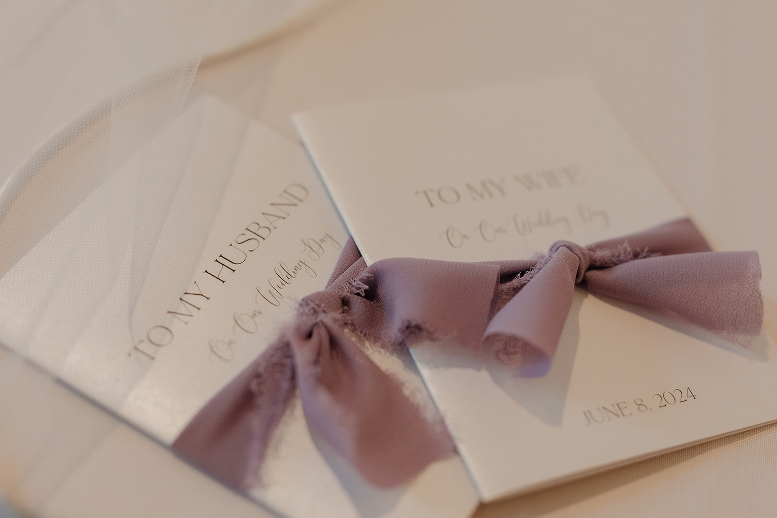 Close-up of wedding vow books tied with soft lavender ribbon
