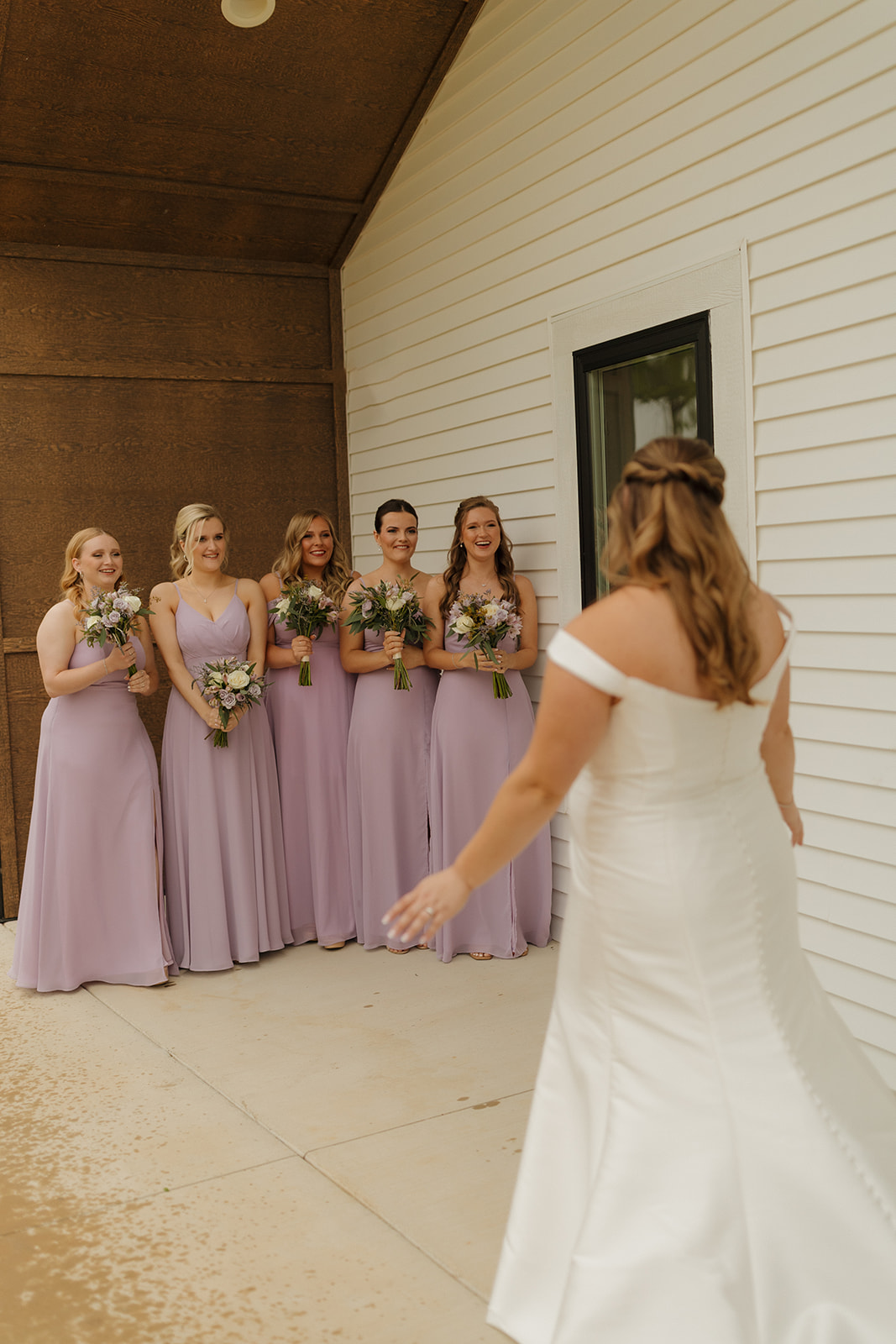 Bride seeing bridesmaids for the first time outside wedding venues in Wisconsin
