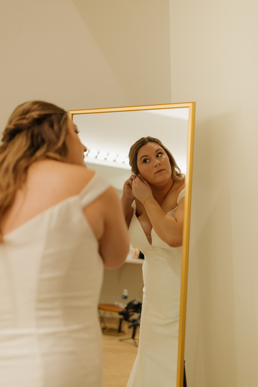 Bride adjusting earrings in mirror before ceremony at wedding venues in Wisconsin