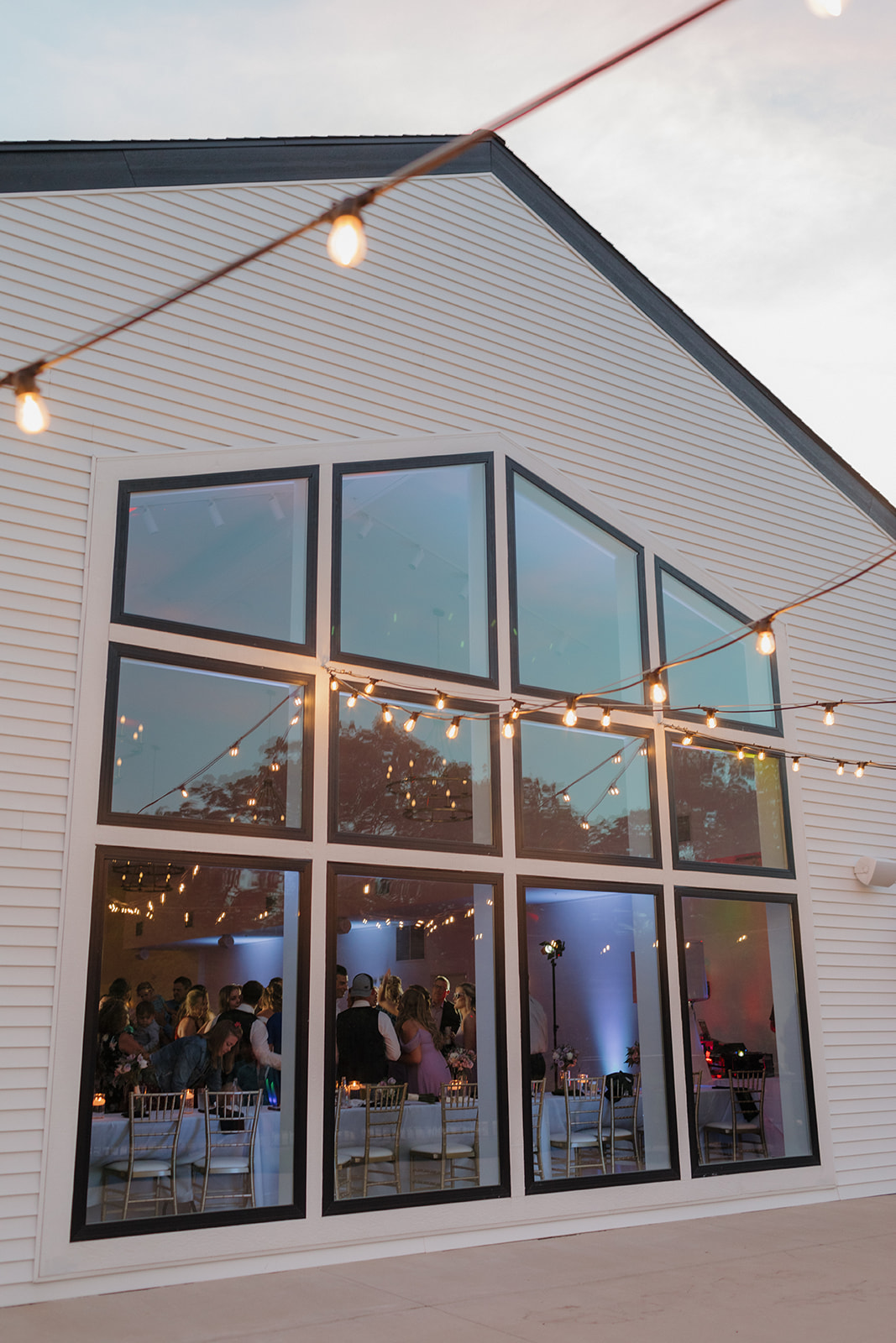 Reception guests visible through large windows at wedding venues in Wisconsin at dusk