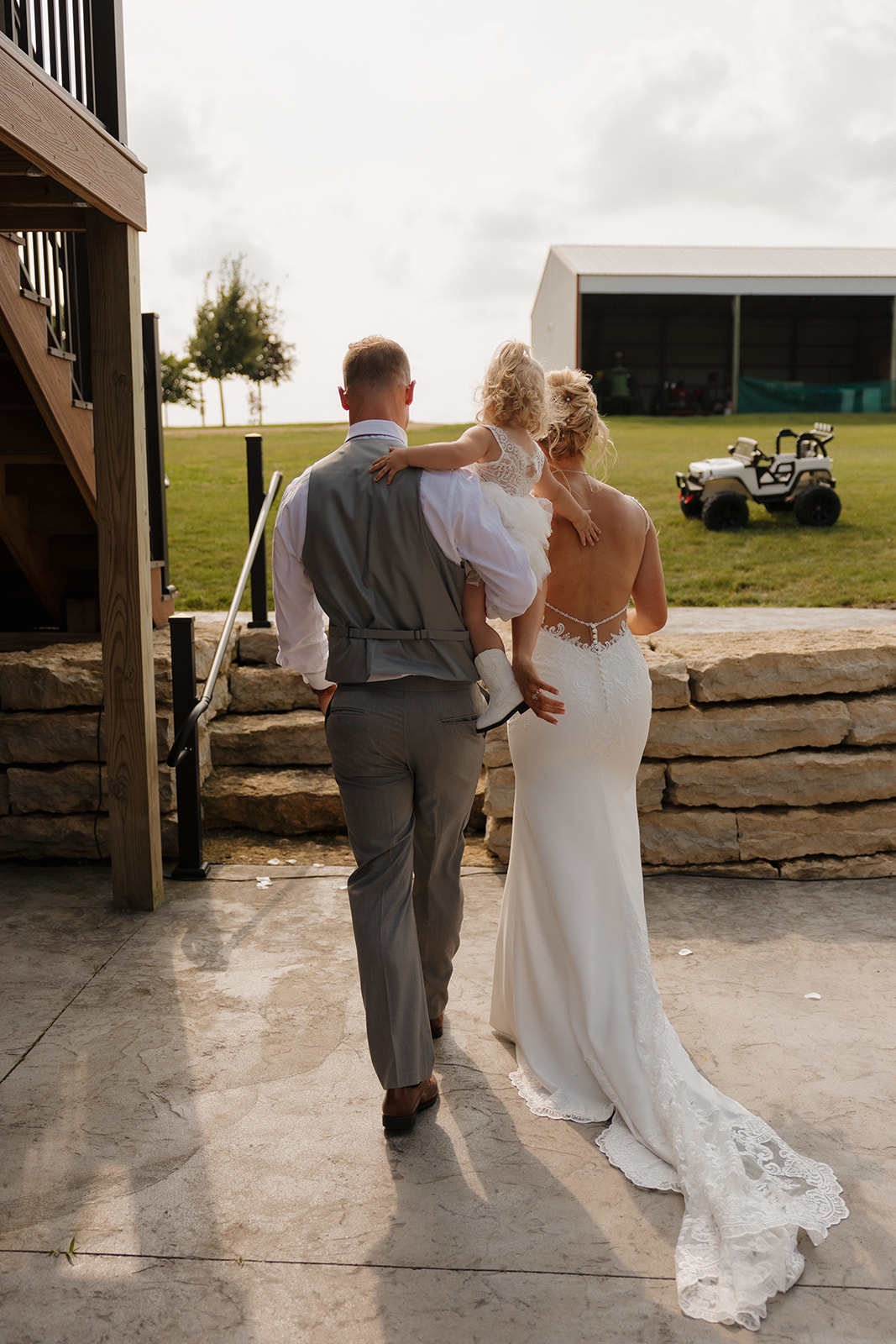 Bride, groom, and their daughter walking hand in hand toward the reception space—family moments belong on every wedding photography checklist.