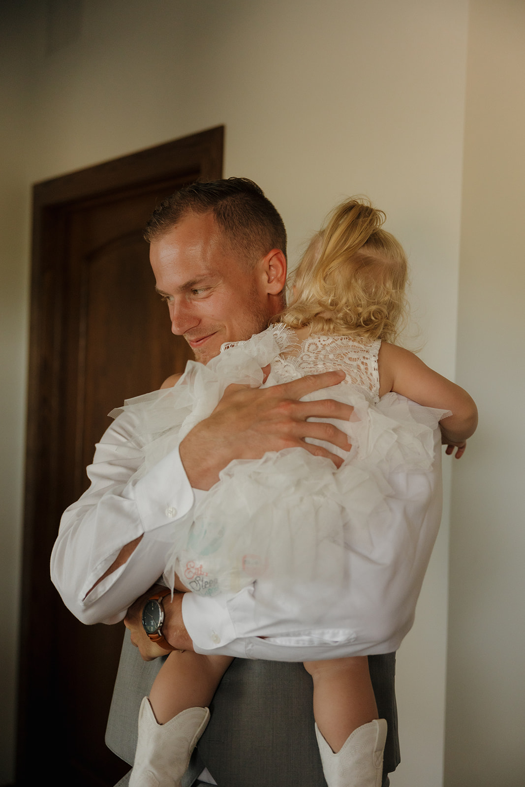 Groom smiling down at his daughter in a mini wedding ride-on car—such a sweet wedding photography checklist moment.