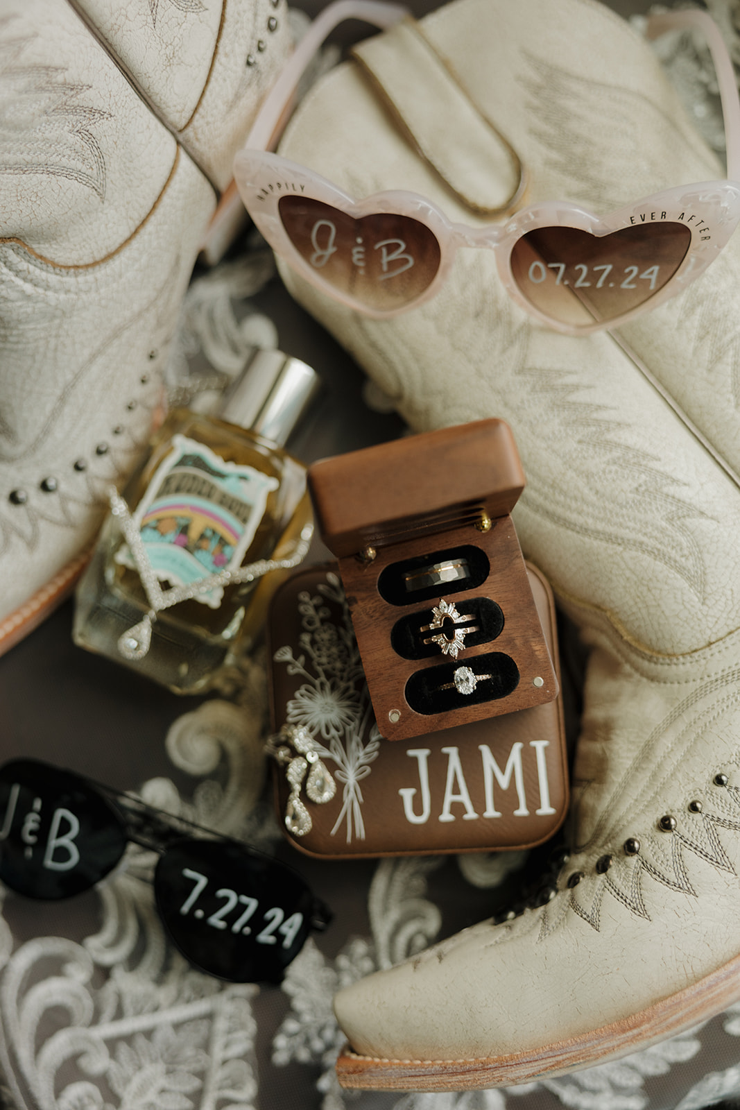 Detail flat lay of custom wedding rings, western boots, sunglasses, and perfume—must-have moment on any wedding photography checklist.