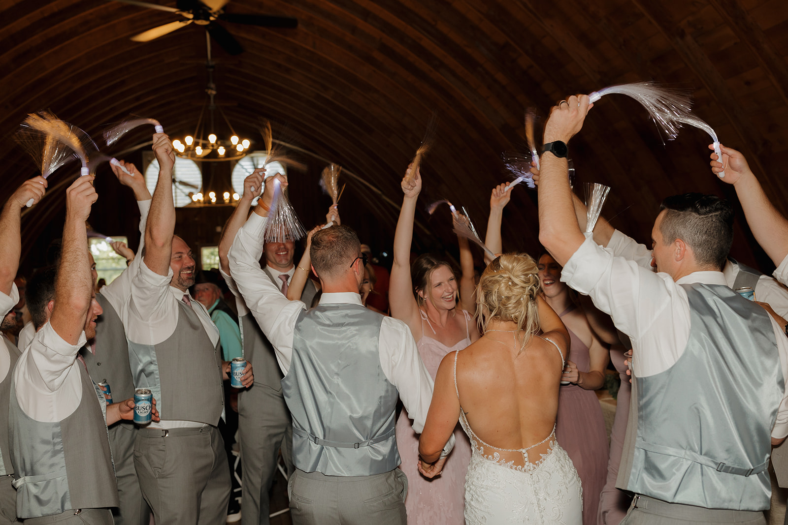 Packed dance floor under chandeliers as guests wave LED streamers—this energy belongs on your wedding photography checklist.