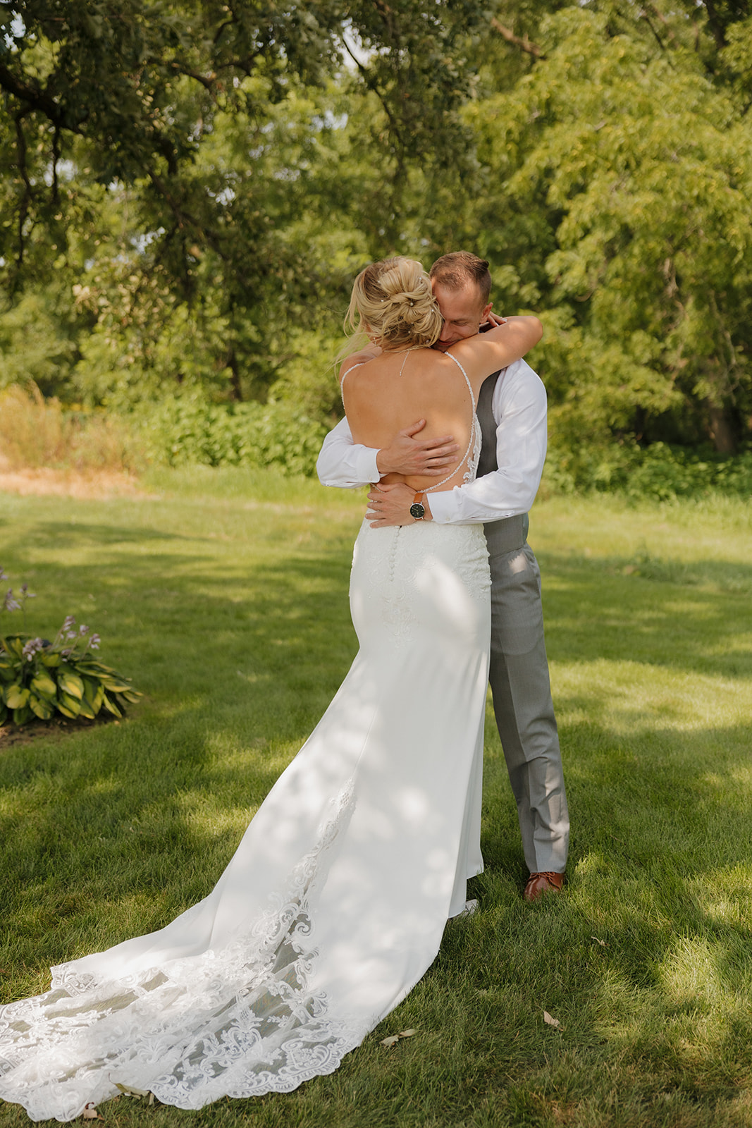 Couple embracing tightly during their private first look, surrounded by lush greenery.