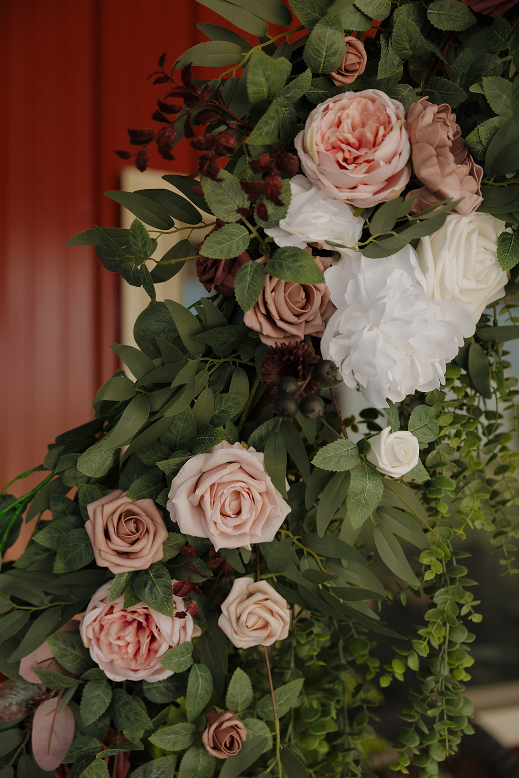 Close-up of blush-toned florals with greenery on the wedding ceremony arch.
