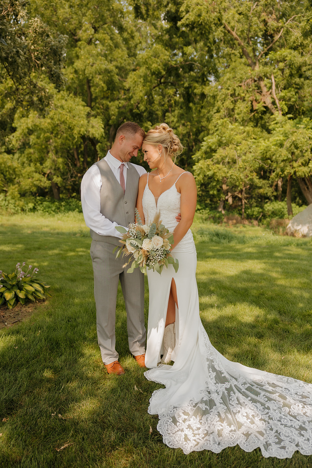 Newlyweds standing close in a wooded outdoor portrait moment during their wedding.