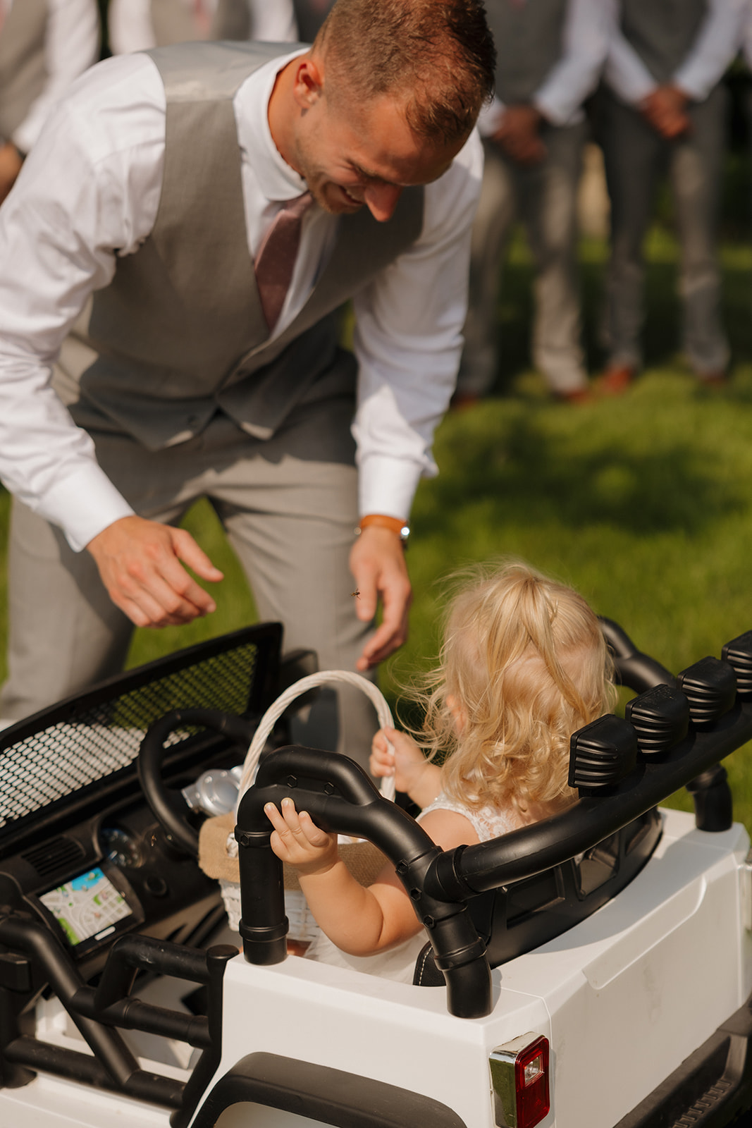 Groom holding his daughter in her white tulle dress and little boots before the ceremony.