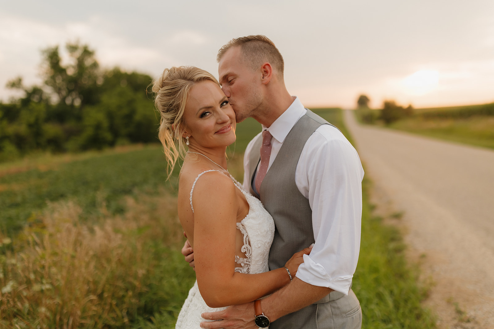 Sunset kiss on a country road with the bride beaming—golden hour portraits always top the wedding photography checklist.