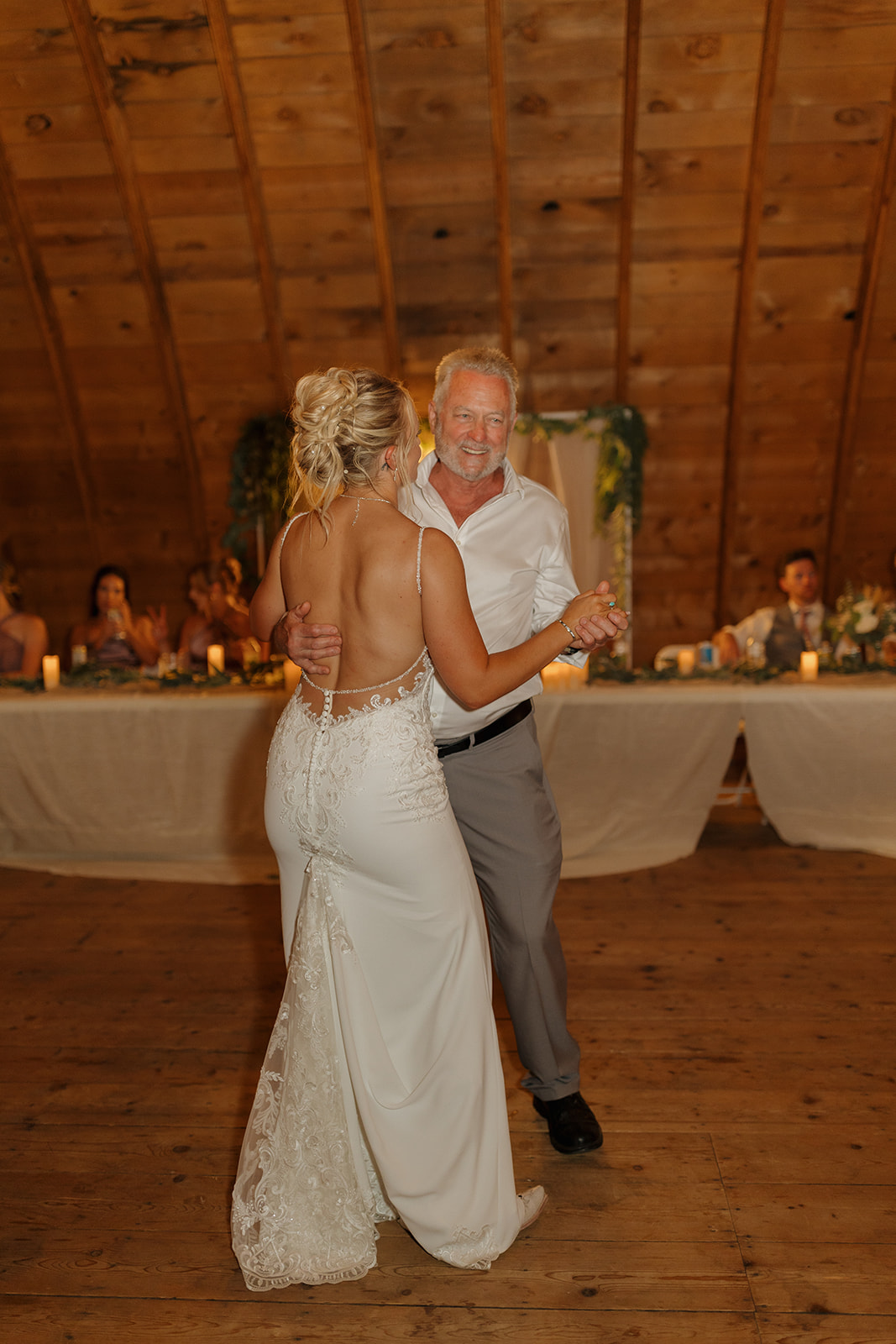 Bride shares a heartfelt father-daughter dance surrounded by warm candlelight.