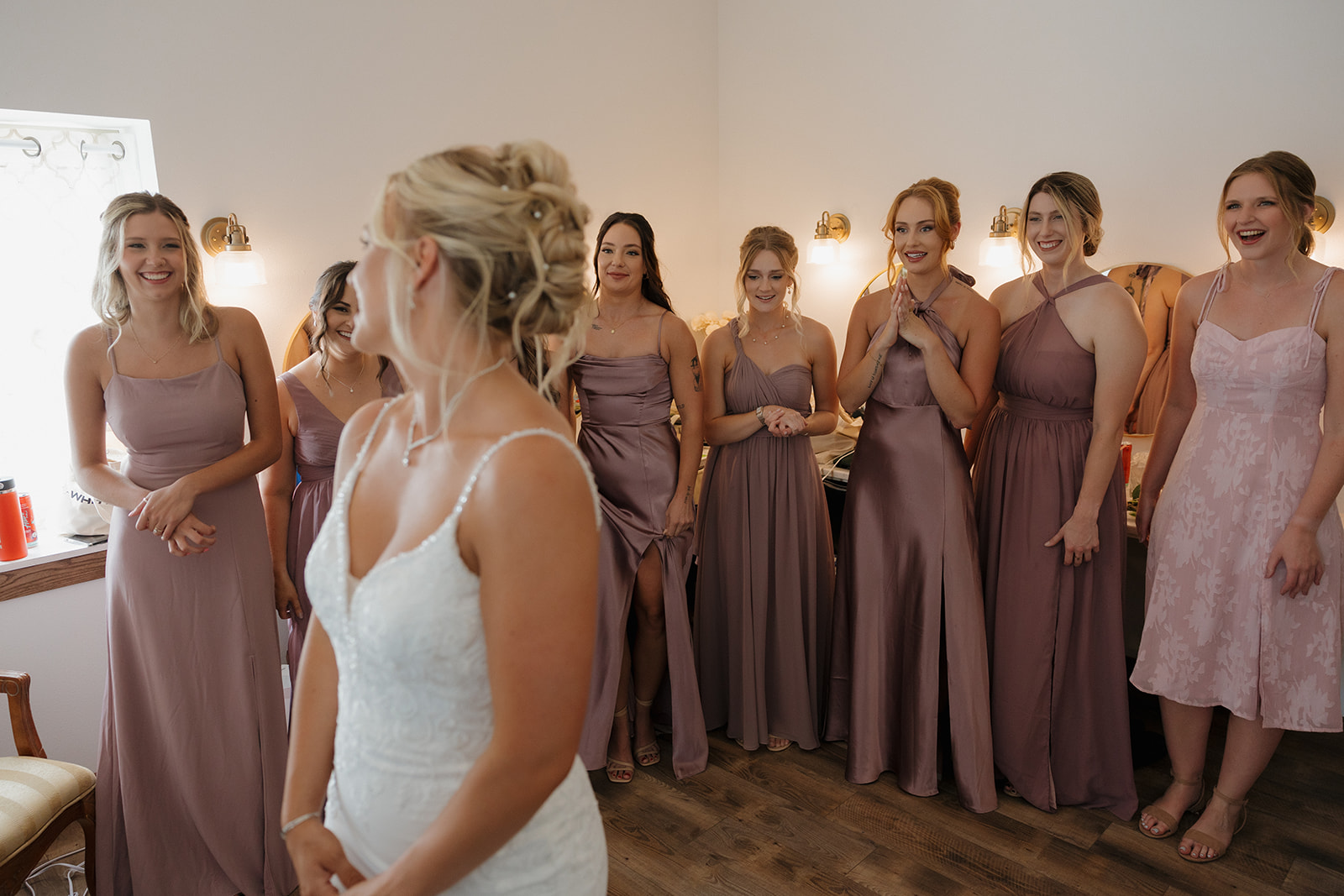 Bride sharing a joyful first look with bridesmaids in mauve dresses—candid moments like this belong on every wedding photography checklist.