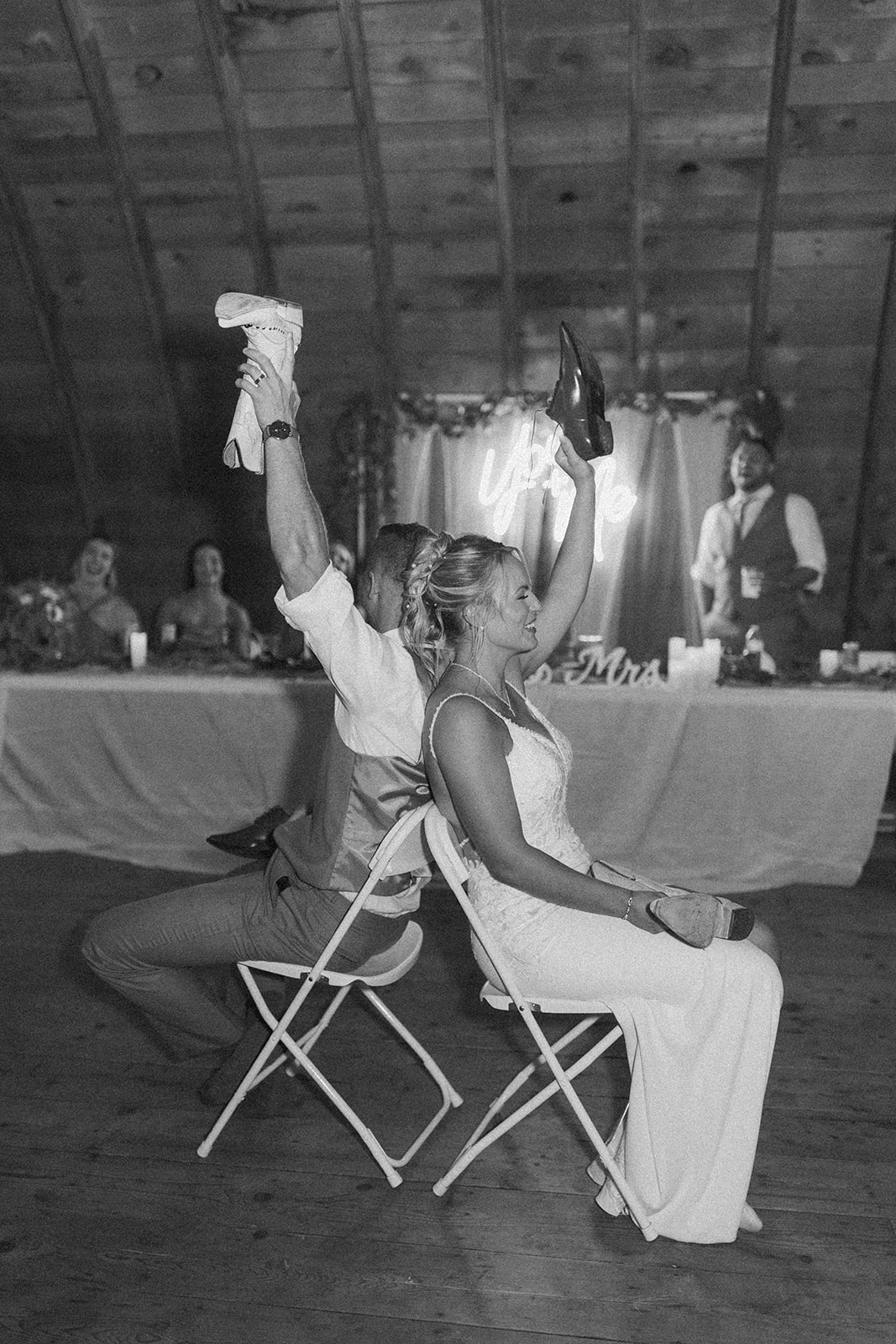 Bride and groom laughing during the shoe game at their rustic barn reception.