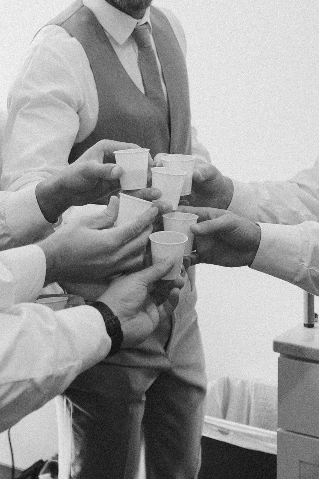 Black and white shot of groomsmen doing a pre-ceremony toast—an intentional storytelling moment on a wedding photography checklist.