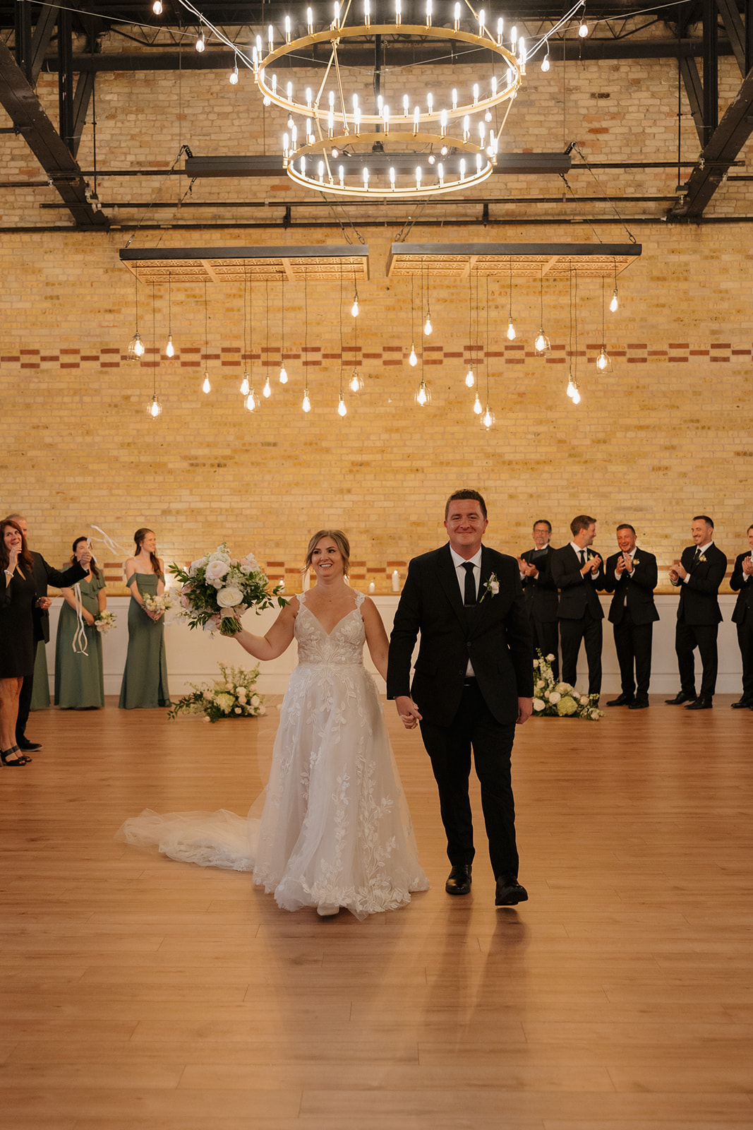 Newlywed couple entering their reception beneath chandeliers and string lights at a wedding venue in Fort Myers Florida