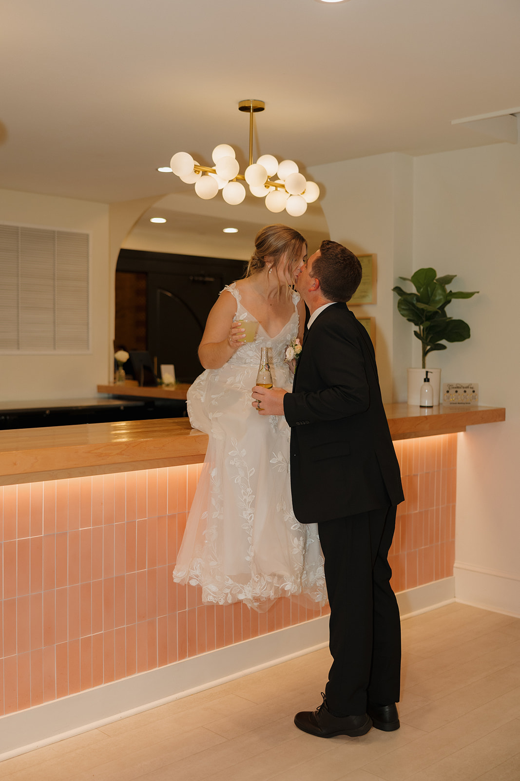 Bride and groom sharing a kiss at a stylish cocktail bar during their wedding reception