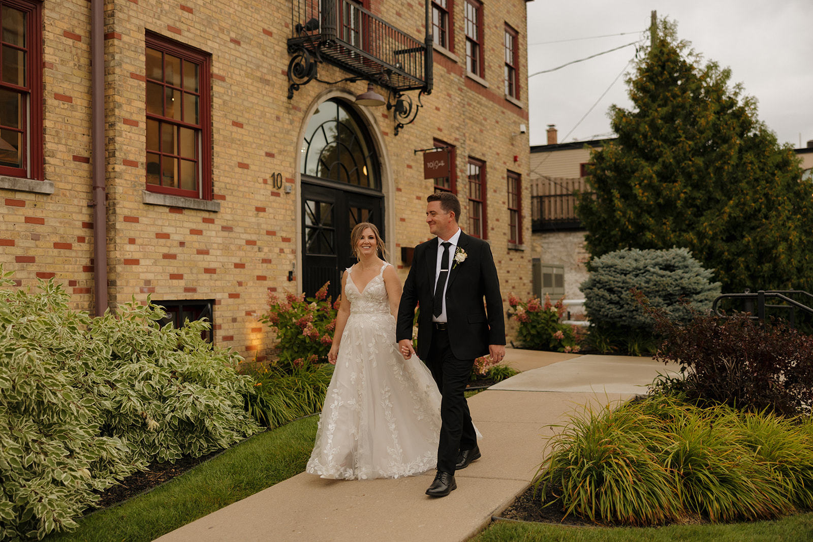 Newlywed couple walking outside a historic brick venue often featured among beautiful wedding venues in Fort Myers