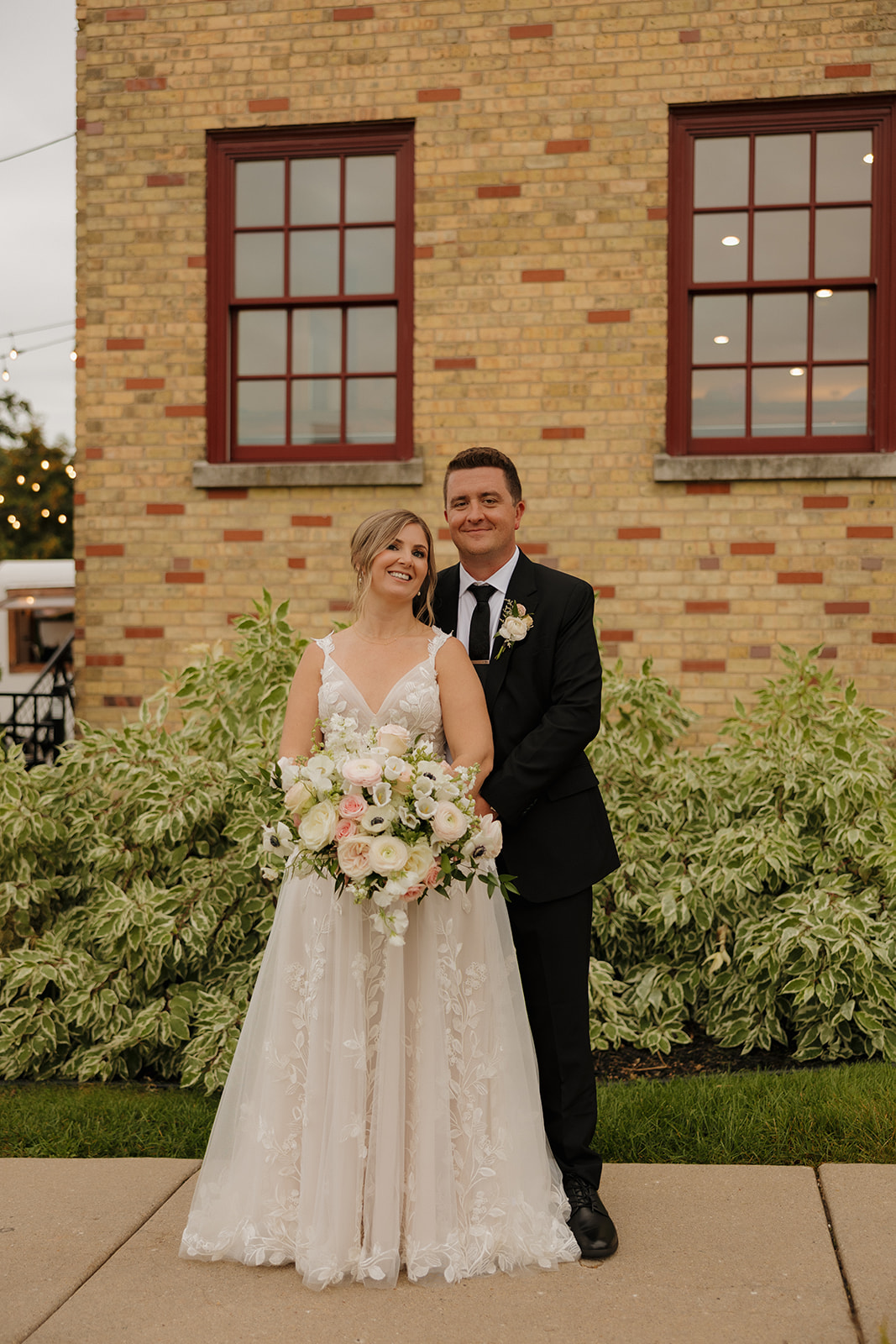 Newlywed couple posing outside a historic brick building at a charming wedding venue