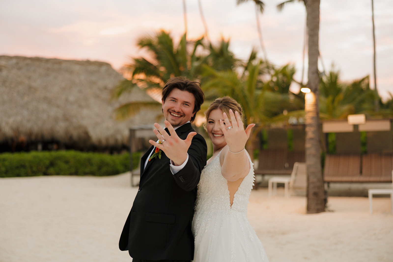 Bride and groom smiling and showing their wedding rings during sunset portraits at a beach wedding venue in Fort Myers.