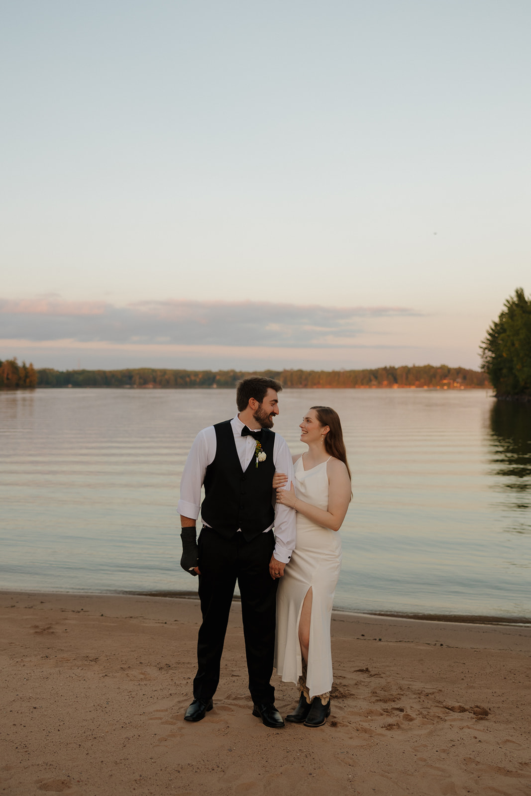 Bride and groom walking along the shoreline at sunset during a beach wedding portrait session
