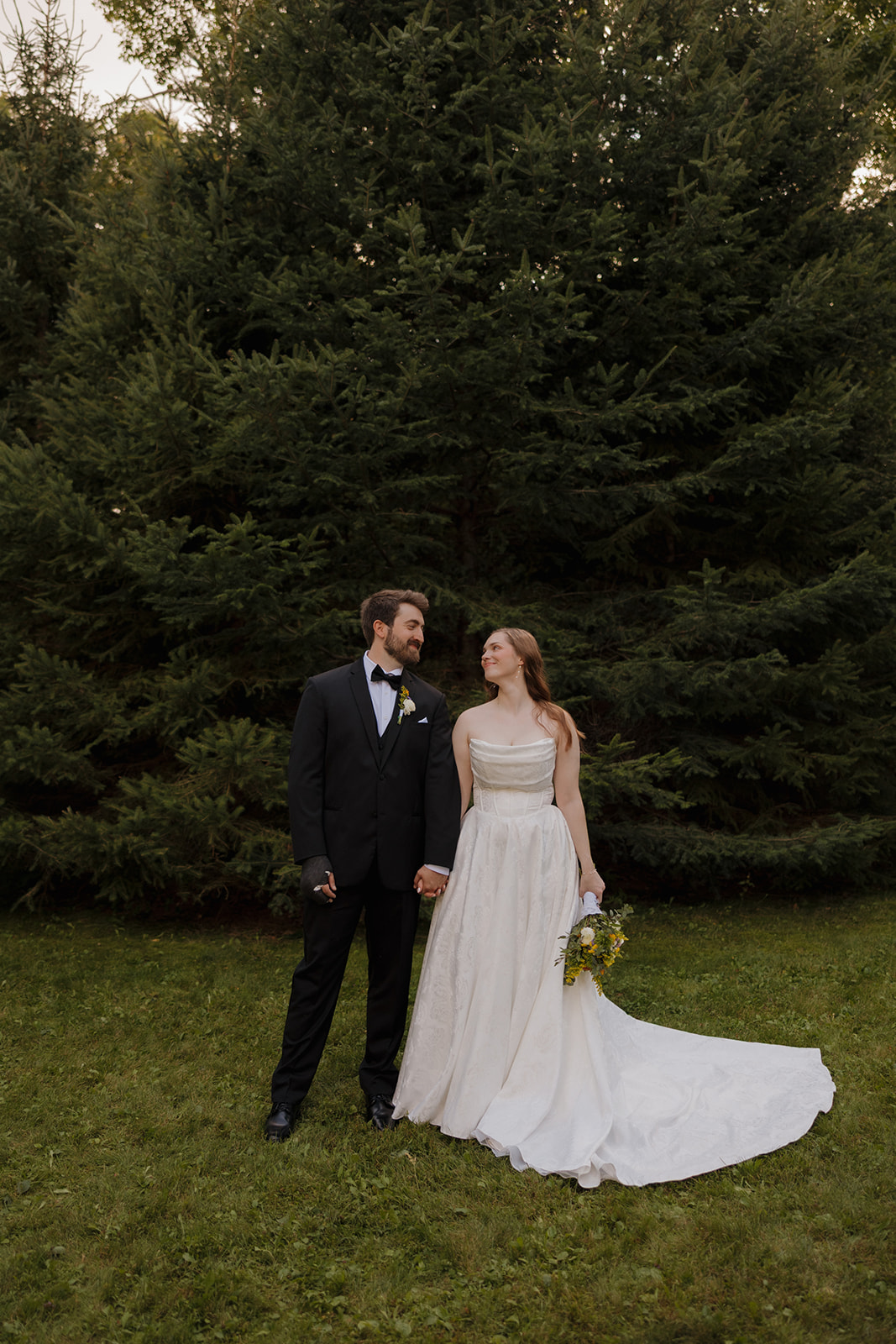 Bride and groom standing together during natural outdoor portraits on a lush green lawn